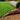 Roll of green artificial grass being installed on a prepared ground surface.