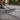 Person using a rake on newly laid gravel or small stones outdoors.